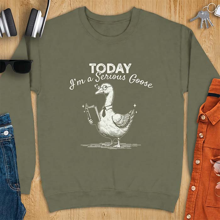 Military Green sweatshirt with an illustration of a goose wearing round glasses and a necktie, holding an open book, next to sparkle accents and the text Today I'm A Serious Goose.