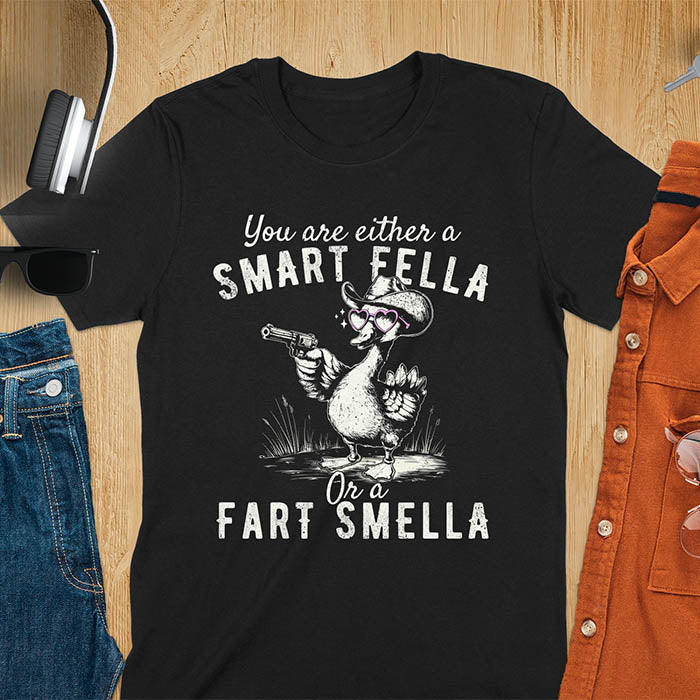 Black color tee with A goose wearing heart shaped glasses and holding a pistol. Text reads You are either a Smart Fella or a Fart Smella.