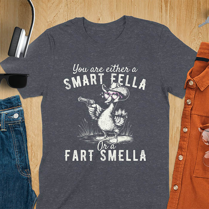 Dark heather color tee with A goose wearing heart shaped glasses and holding a pistol. Text reads You are either a Smart Fella or a Fart Smella.