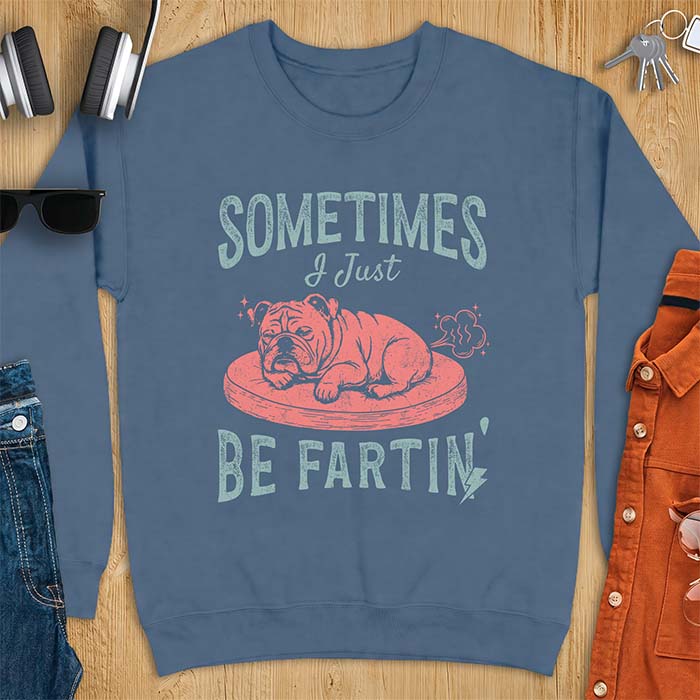 Indigo Blue sweatshirt with a graphic of a sleeping English Bulldog curled up on a dog bed with a fart cloud drawn behind it beside the text Sometimes I Just Be Fartin