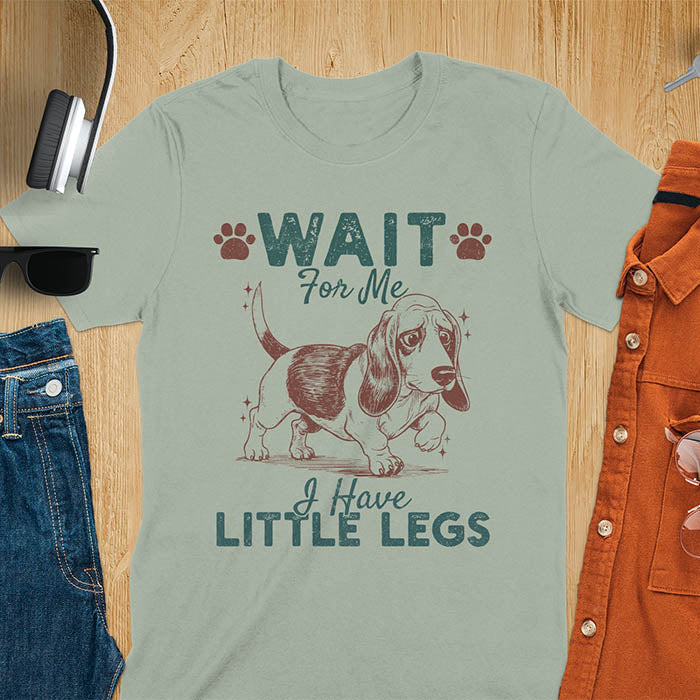Basset hound meme t-shirt with dog illustration and text Wait For Me I Have Little Legs with paw prints - sage green