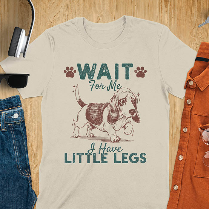Basset hound meme t-shirt with dog illustration and text Wait For Me I Have Little Legs with paw prints - sand color