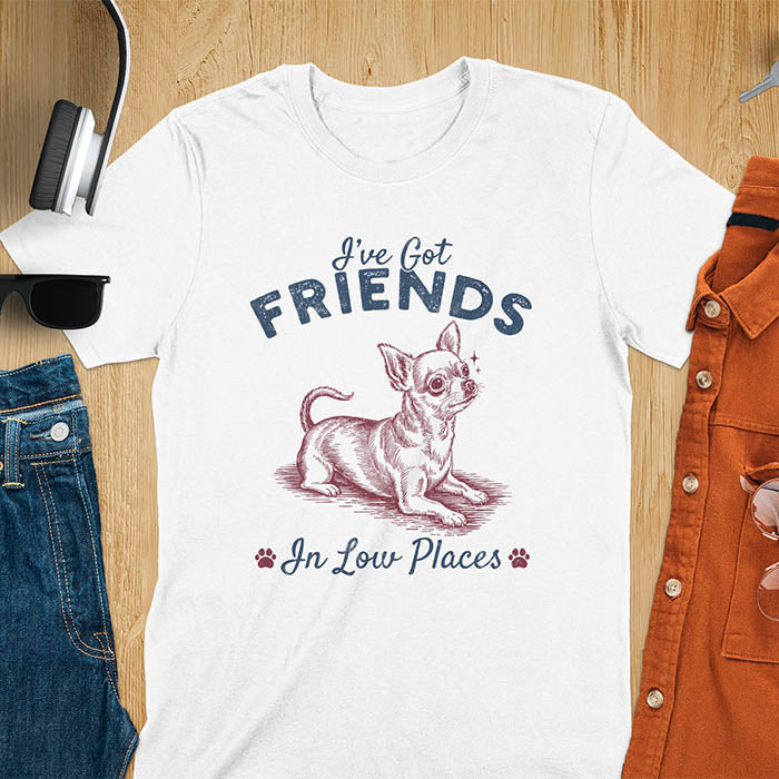 White t-shirt featuring a sitting chihuahua illustration with large ears and paw prints, text reads I've Got Friends In Low Places